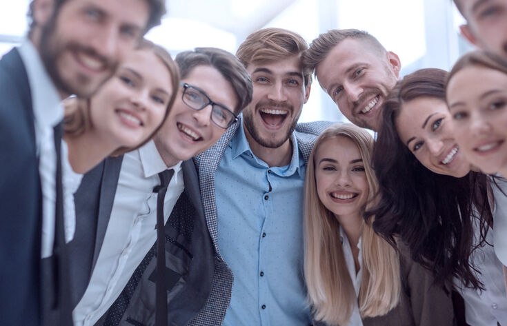 Menschen im Kreis die begeistert in die Kamera gucken