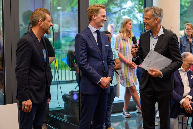Markus Bünnemeyer (m.) erhält seinen Preis von Markus Schmitz (r.), Vorsitzender Textile and Fashion Network e.V.