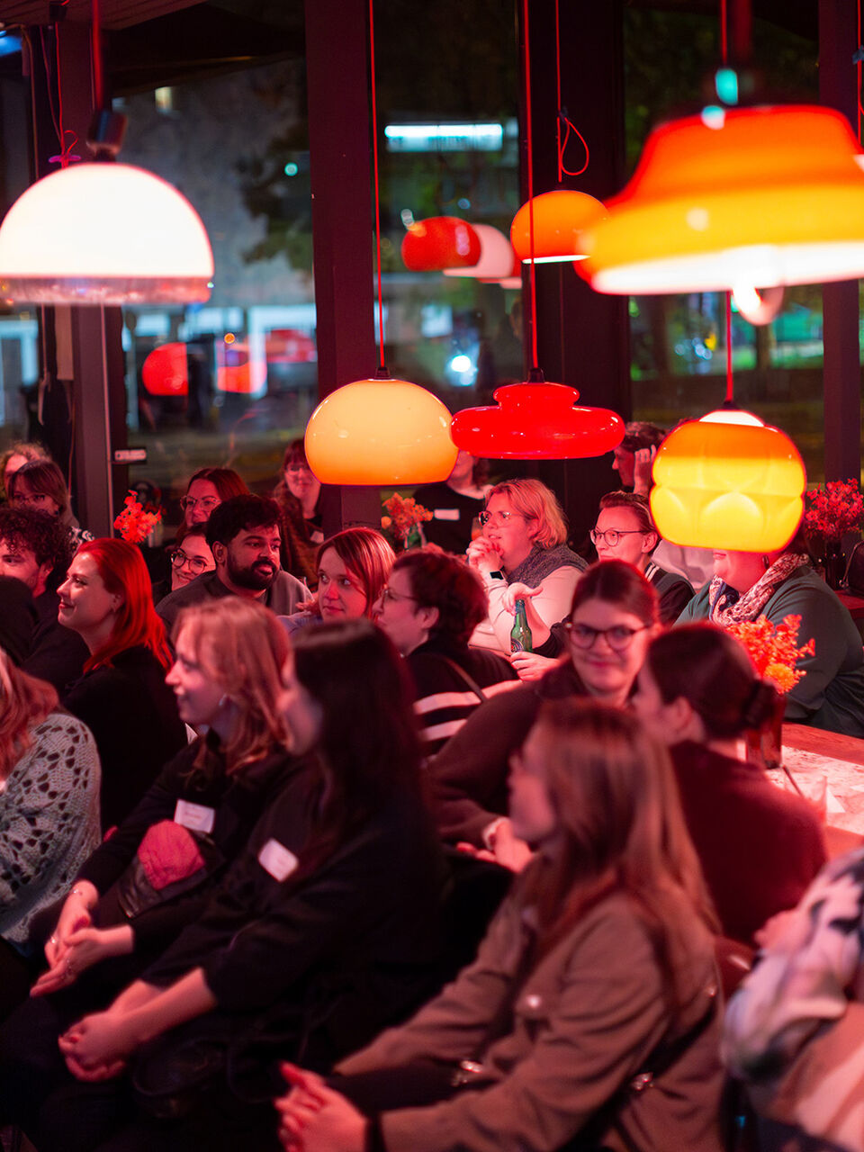 Menschen die an langen Tischen sitzen unter warmen Licht