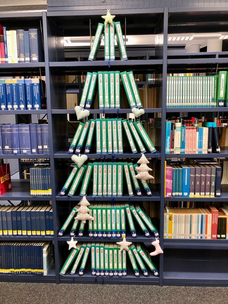 Grüne Bücher die wie ein Weihnachtsbaum im Regal angeordnet wurden