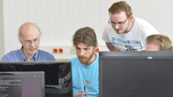 Vier Männer schauen auf einen Monitor