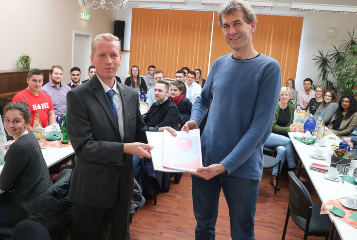 Dr. Markus Profijt übergibt im Beisein der Studierenden den Bericht an Matthias Merbecks, Geschäftsführer des Volksvereins. 